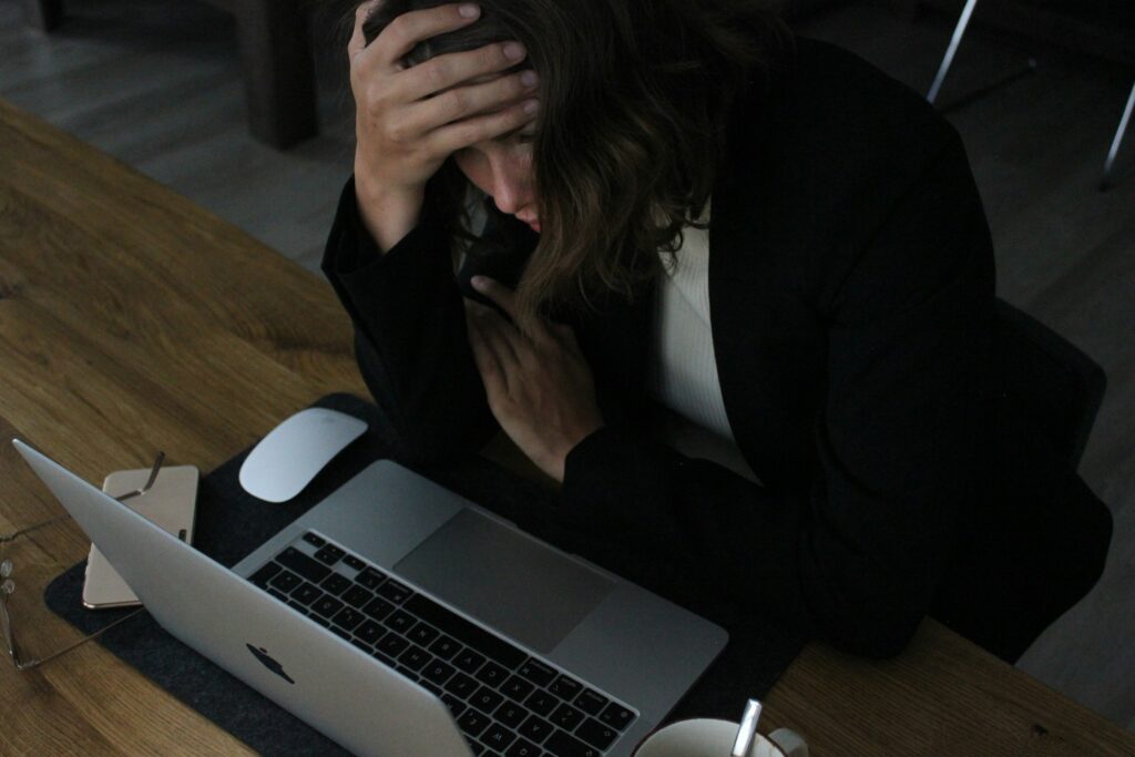 An employee sitting at a desk with head in hand, showing signs of work-related stress